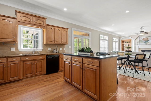 kitchen featuring light wood finished floors, ornamental molding, a sink, a center island, and black dishwasher