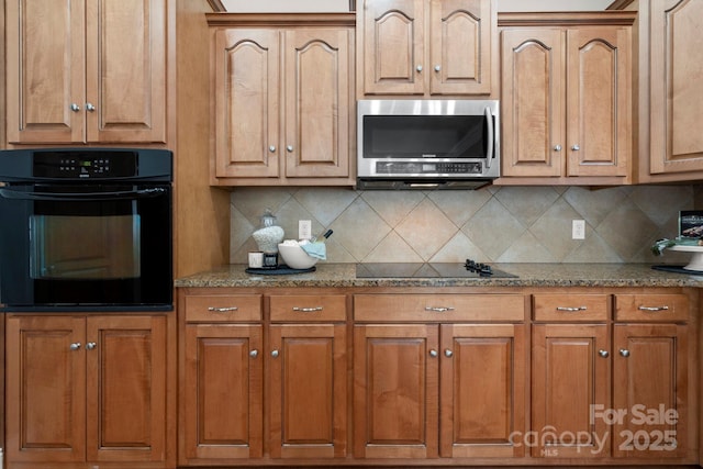 kitchen with brown cabinetry, black appliances, decorative backsplash, and light stone countertops