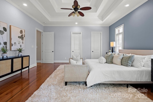 bedroom with a tray ceiling, baseboards, recessed lighting, wood finished floors, and ornamental molding