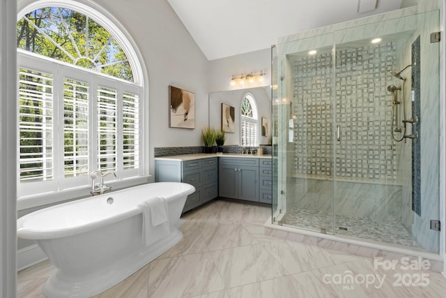 bathroom with a shower stall, marble finish floor, vaulted ceiling, vanity, and a soaking tub