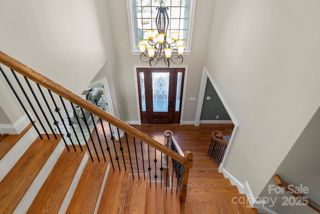 entrance foyer with wood finished floors, a high ceiling, a notable chandelier, and stairway