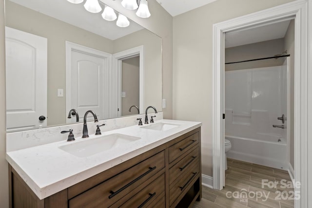 full bath with double vanity, toilet, wood finished floors, and a sink