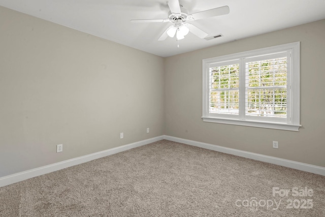 carpeted spare room with visible vents, a ceiling fan, and baseboards