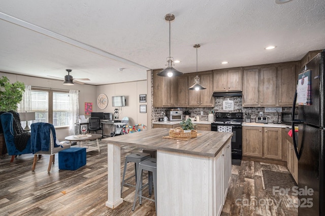 980 Lakeland Ave, Lincolnton, NC 28092 - kitchen with wooden counters, a center island, dark wood finished floors, under cabinet range hood, and black appliances