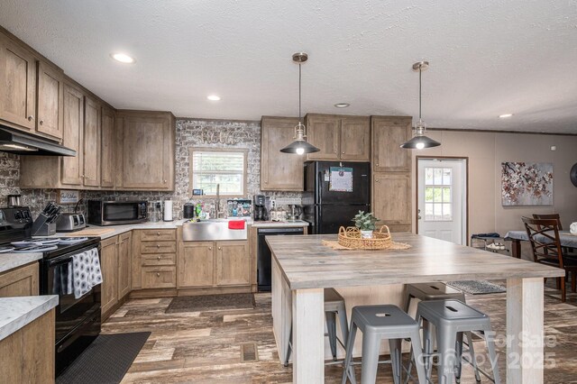 980 Lakeland Ave, Lincolnton, NC 28092 - kitchen featuring decorative backsplash, a kitchen bar, under cabinet range hood, a sink, and black appliances