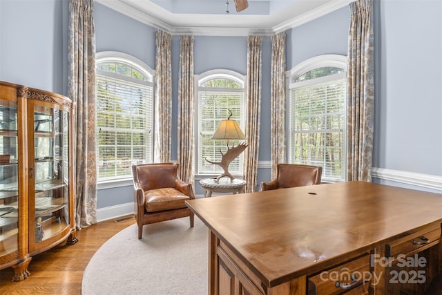 office area featuring crown molding, light wood-style flooring, a ceiling fan, visible vents, and baseboards
