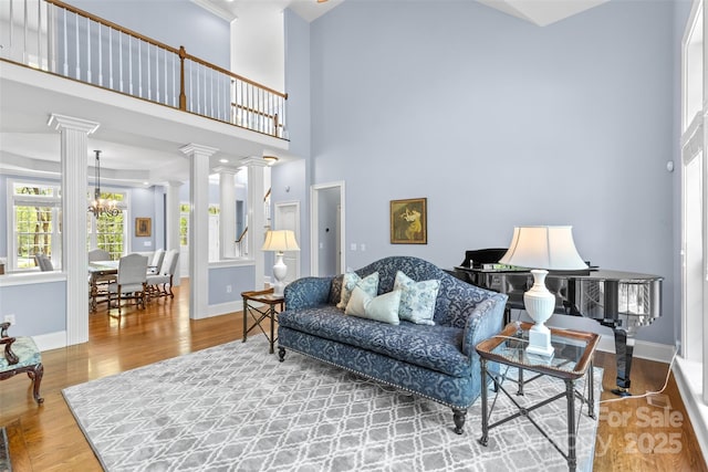 living area with a chandelier, ornate columns, baseboards, and wood finished floors