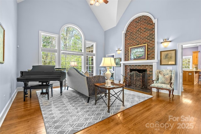 living area featuring a wealth of natural light, high vaulted ceiling, wood finished floors, and a ceiling fan
