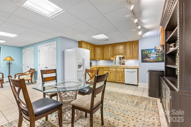 dining room with light tile patterned floors, baseboards, a drop ceiling, and track lighting