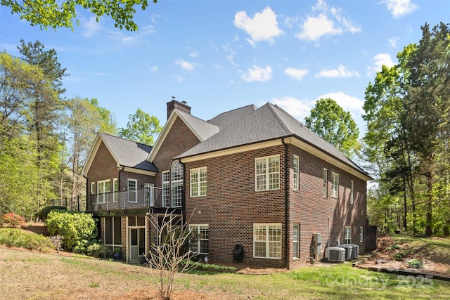 back of house featuring a yard, brick siding, a deck, and a chimney
