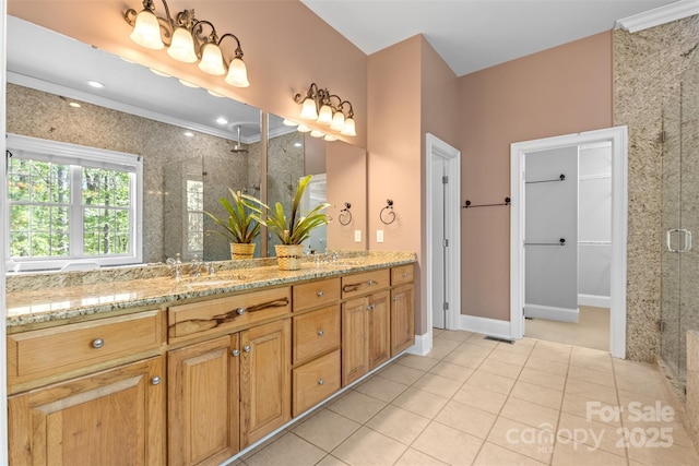 bathroom featuring a shower stall, double vanity, a sink, and tile patterned flooring