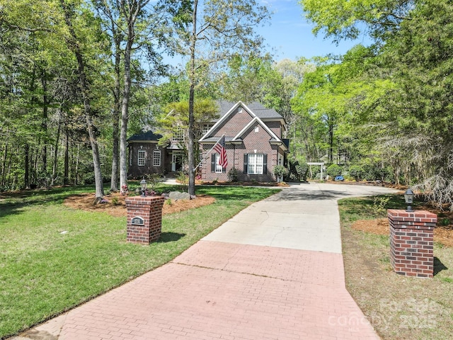 view of front of house with a front yard, brick siding, and decorative driveway