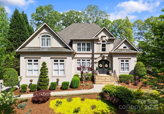 craftsman-style home featuring roof with shingles, french doors, stucco siding, a standing seam roof, and metal roof