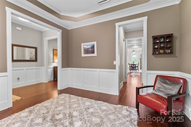 sitting room featuring ornamental molding, wainscoting, wood finished floors, and visible vents