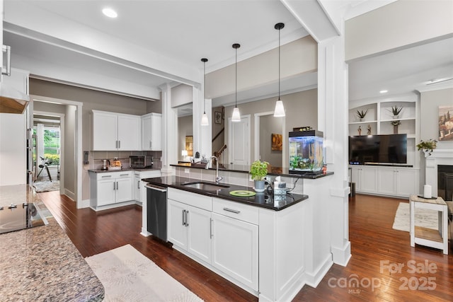 kitchen featuring dark wood-style floors, a sink, dishwasher, backsplash, and pendant lighting