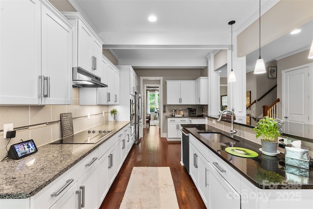 kitchen with a sink, black electric cooktop, dark wood finished floors, decorative backsplash, and under cabinet range hood