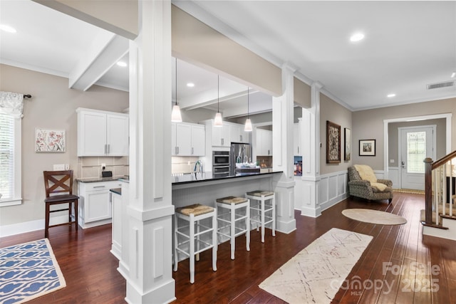 kitchen featuring stainless steel fridge, a healthy amount of sunlight, a breakfast bar, and visible vents