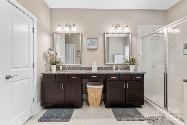 full bathroom featuring double vanity, a shower stall, and a sink