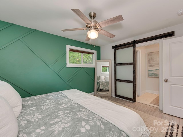 7048 Delta Lake Dr, Charlotte, NC 28215 - bedroom with a barn door, a ceiling fan, and wood finished floors