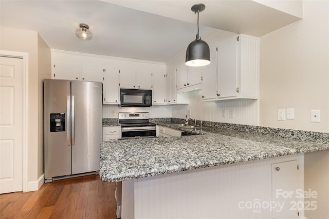 kitchen with light stone counters, a peninsula, dark wood finished floors, stainless steel appliances, and white cabinets