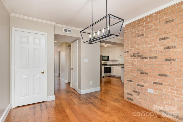 unfurnished dining area with light wood-style flooring, a notable chandelier, crown molding, and visible vents
