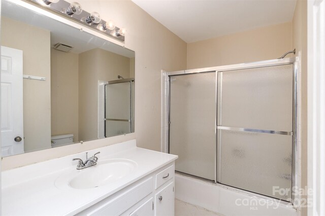 full bath with visible vents, toilet, shower / bath combination with glass door, and vanity