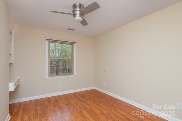 unfurnished room with a ceiling fan, wood finished floors, baseboards, and visible vents