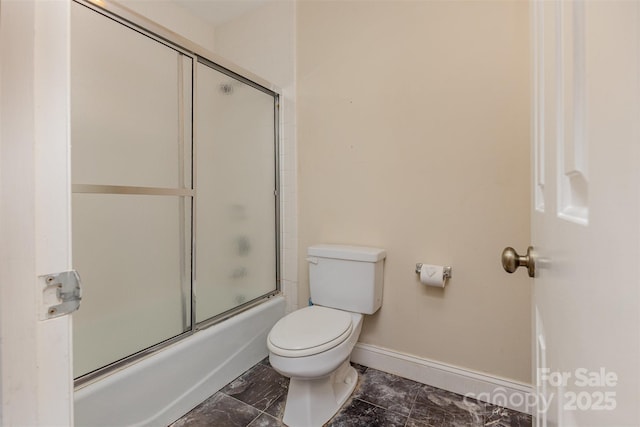 full bath with baseboards, toilet, and shower / bath combination with glass door