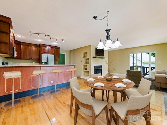 234 Bird Creek Dr, Waynesville, NC 28786 - dining area with a chandelier, light wood finished floors, a fireplace, and built in shelves