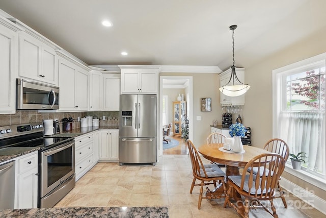 kitchen with stainless steel appliances, dark stone counters, backsplash, and white cabinetry