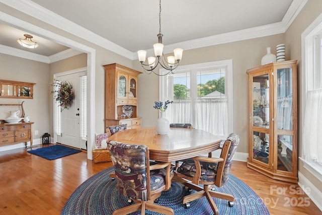 dining space featuring a chandelier, light wood-style flooring, baseboards, and ornamental molding