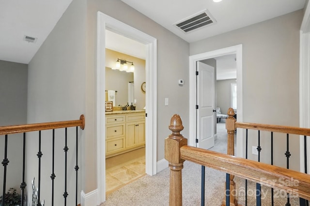 corridor featuring light carpet, baseboards, visible vents, and an upstairs landing