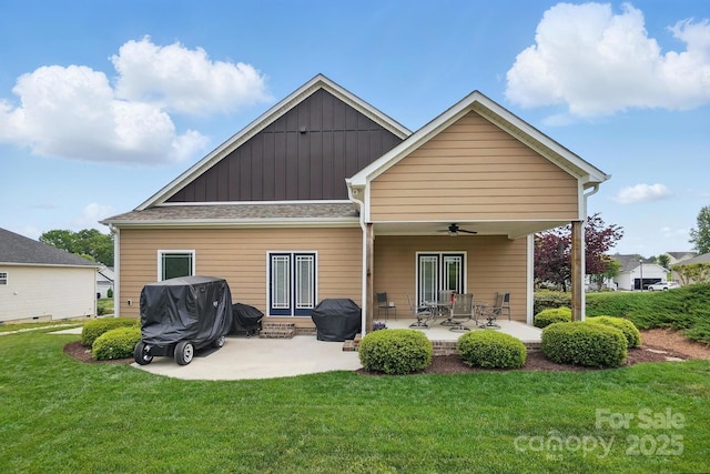 rear view of house with board and batten siding, a lawn, a ceiling fan, and a patio