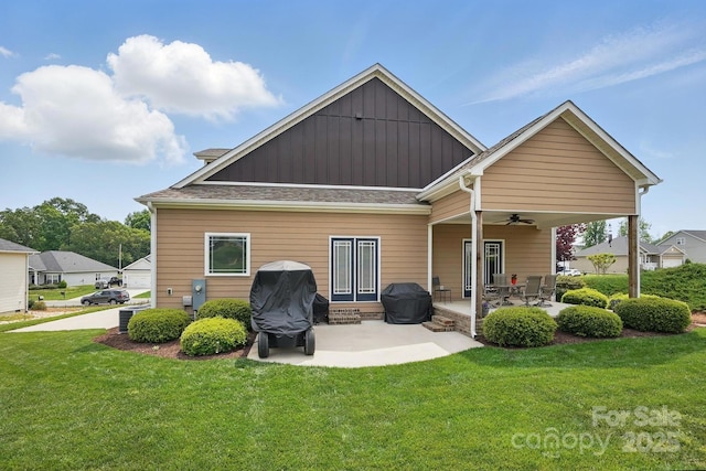 back of property featuring board and batten siding, a yard, a patio, and ceiling fan