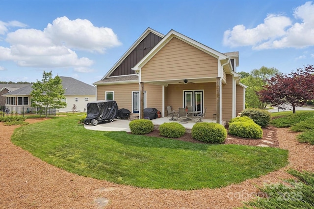 back of property featuring fence, a patio area, ceiling fan, board and batten siding, and a yard