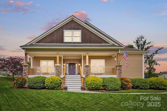 view of front of property with roof with shingles, a porch, a yard, and board and batten siding