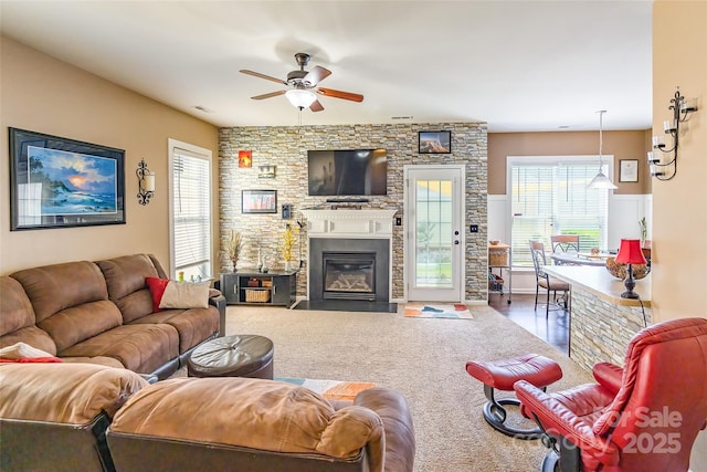 living room featuring a healthy amount of sunlight, a fireplace, a ceiling fan, and visible vents