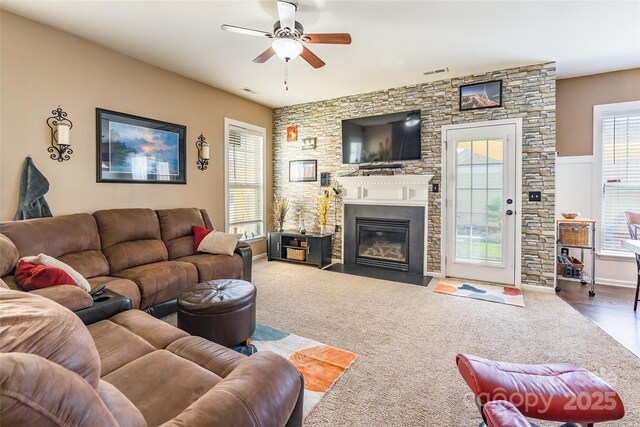 living room featuring visible vents, a large fireplace, and ceiling fan