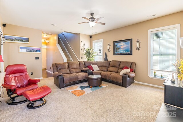 carpeted living room featuring baseboards, a ceiling fan, visible vents, and stairs