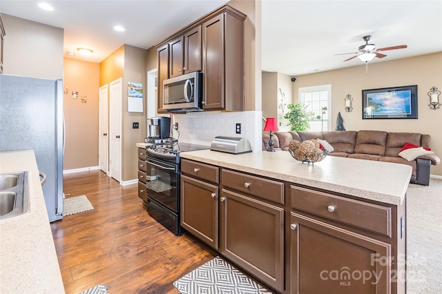 kitchen featuring open floor plan, appliances with stainless steel finishes, light countertops, and dark wood finished floors