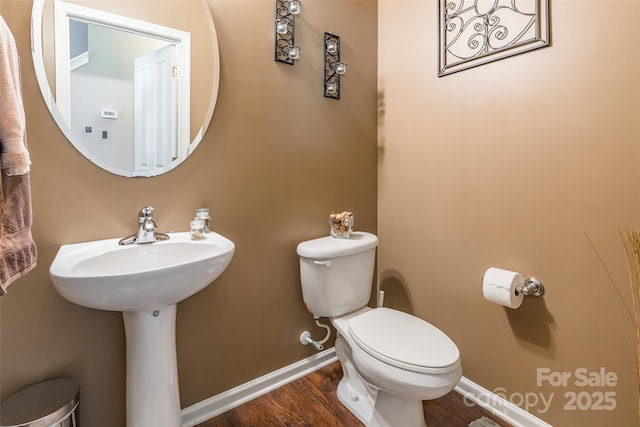 half bath featuring toilet, wood finished floors, and baseboards