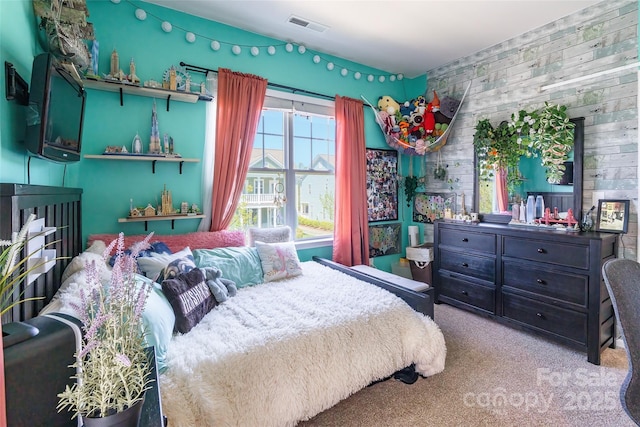 bedroom with wood walls, visible vents, and carpet floors