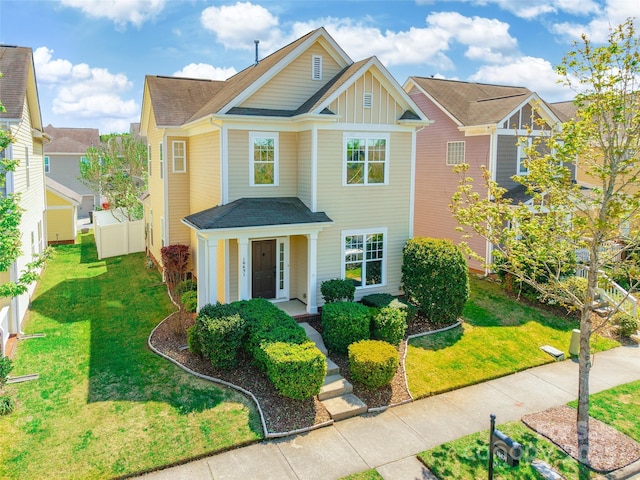 traditional-style home with board and batten siding, a front lawn, and fence