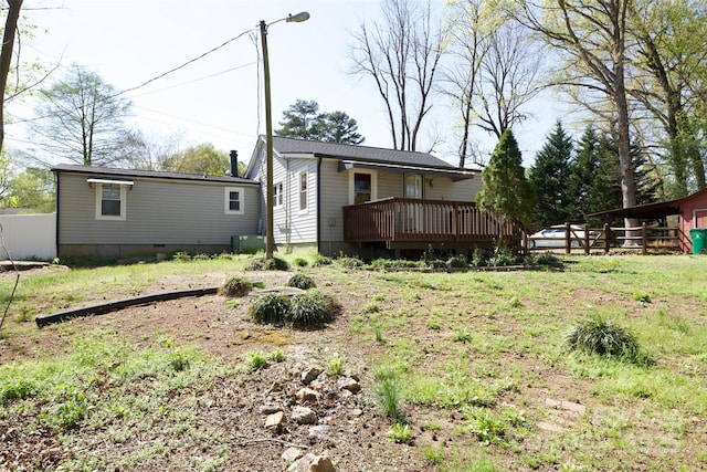 view of yard with central AC unit, fence, and a deck