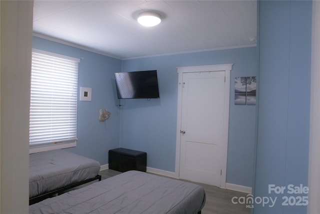 bedroom featuring baseboards, ornamental molding, wood finished floors, and a closet