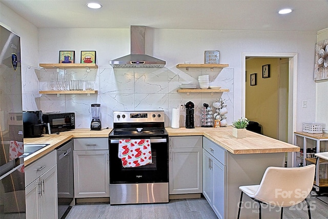 kitchen with open shelves, black microwave, wall chimney exhaust hood, butcher block counters, and electric range