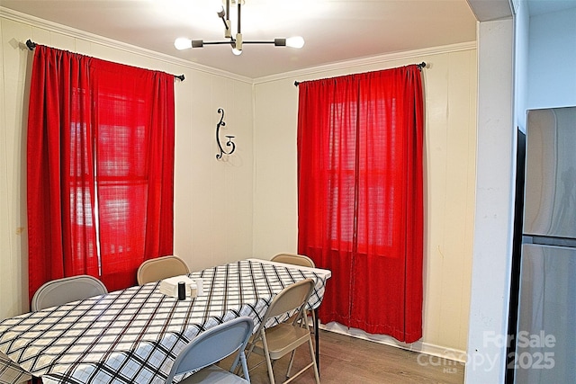 dining space with ornamental molding, wood finished floors, and an inviting chandelier