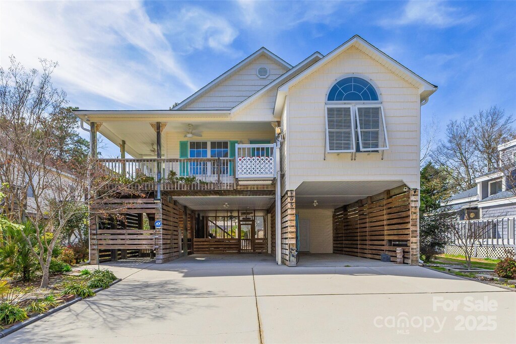 105 SW 3rd St, Oak Island, NC 28465 - view of front facade featuring concrete driveway, stairway, ceiling fan, a porch, and a carport