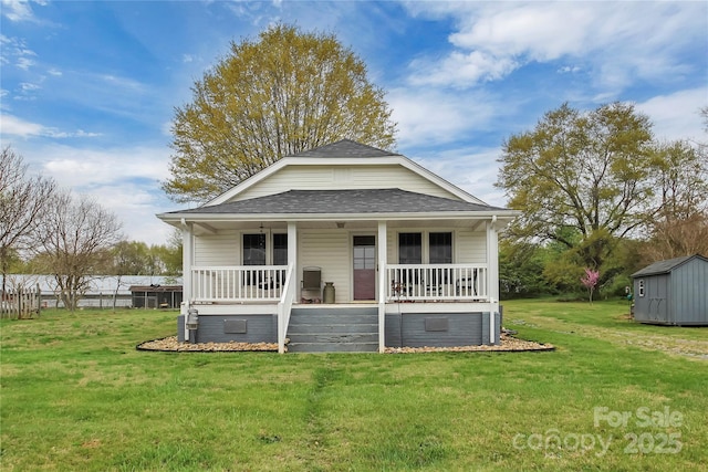 bungalow-style home featuring roof with shingles, an outdoor structure, a storage shed, a front lawn, and a porch