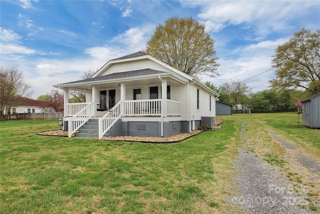 view of front facade featuring a front yard, a porch, central AC, and a shingled roof